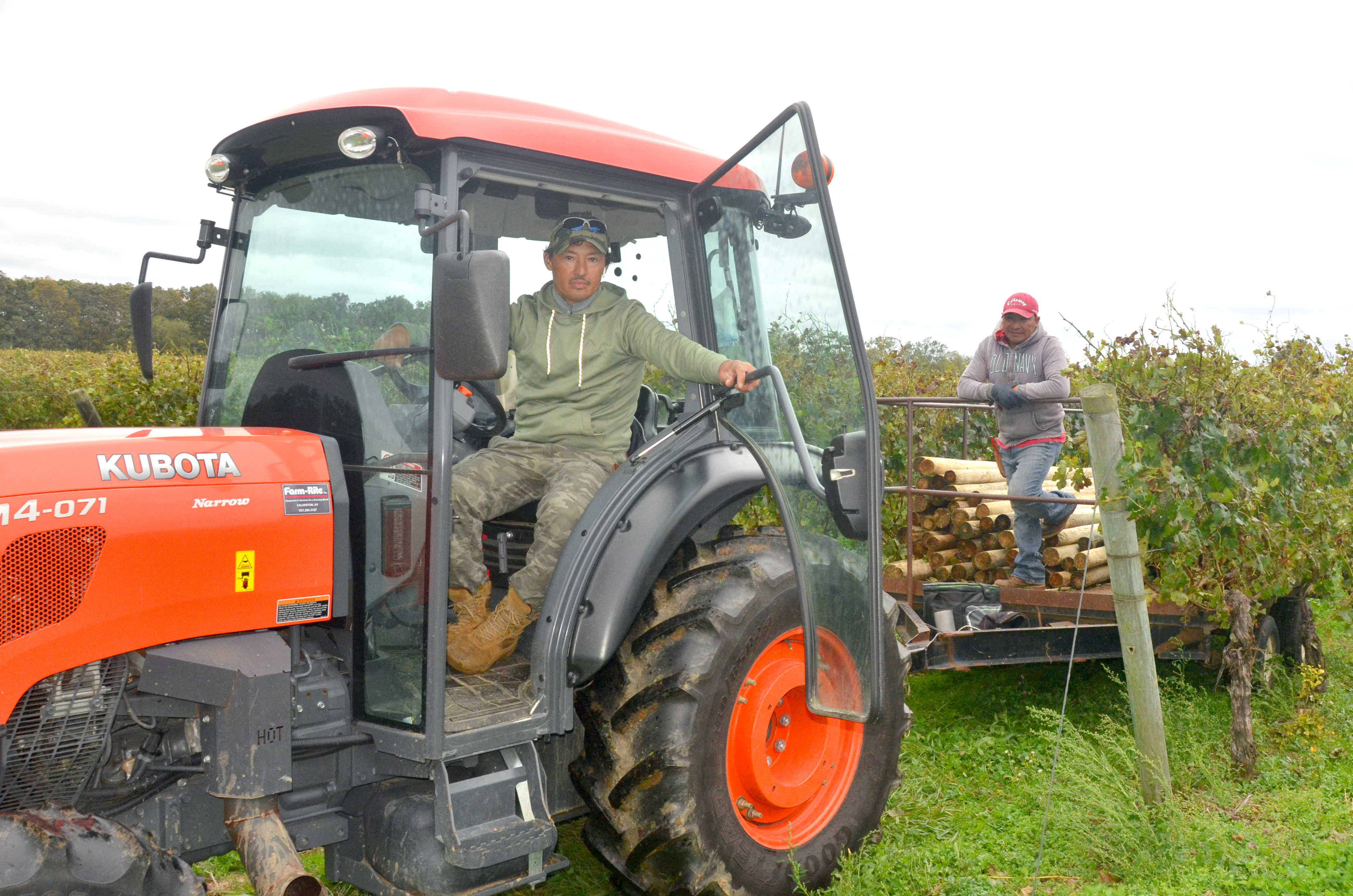 two members sitting on a tractor in the vineyard 
